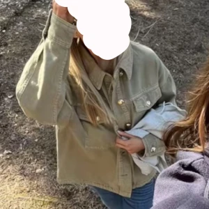 Grön jeansjacka med guldknappar - Säljer en grön jeansjacka med klassisk krage och stora bröstfickor. Jackan har guldiga knappar framtill och vid ärmsluten. Rak passform och långärmad, perfekt att slänga över en hoodie eller t-shirt.