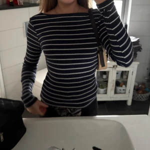 Mörkblå randig tröja med vita ränder - Säljer en mörkblå långärmad tröja med vita horisontella ränder. Tröjan har en klassisk passform och rund halsringning. Perfekt för en stilren vardagslook.