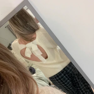 Vit ribbad tröja med rosett och öppen rygg - Säljer en söt vit ribbad tröja med lång ärm och en fin öppen rygg med stor rosett. Tröjan har en mjuk känsla och passar perfekt till både jeans och kjol. Enkel men med en snygg detalj i ryggen.