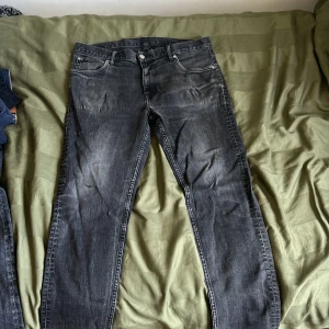 Svarta jeans från Weekday - Säljer ett par svarta jeans från Weekday med klassisk femficksdesign och raka ben. Jeansen har normal passform och är tillverkade i denim med tydliga slitningar för en cool look. Perfekta för dig som gillar en avslappnad stil.