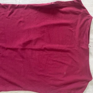 Vinröd tight linnetopp - Säljer en vinröd tight linnetopp i mjukt bomullsmaterial. Toppen är ärmlös och har en enkel, klassisk design som passar perfekt till jeans eller kjol.