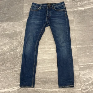 Blå jeans från Neuw - Säljer ett par klassiska blå jeans från Neuw med raka ben och femficksdesign. Jeansen har orange kontrastsömmar och normal passform. Perfekta för dig som gillar stilrena och tidlösa jeans.