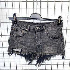 Levis korta jeansshorts - Svarta jeansshorts från Levi's med slitna detaljer och råa fransar längs bensluten. Klassisk femficksmodell med knapp och dragkedja framtill. Strl: S, W 26 på lapp. Mått: Midja 76 cm.  /  Spara skärmtid, besök våra butiker i Sthlm, Malmö & Gbg. New arrivals daily + studentrabatt i alla våra butiker! Hitta till din närmsta butik på humansecondhand.se.   HUMANA Second Hand erbjuder 14 dagars retur, även via plick. Returer skickas med PostNord. Vid retur kontakta support@plick.se.