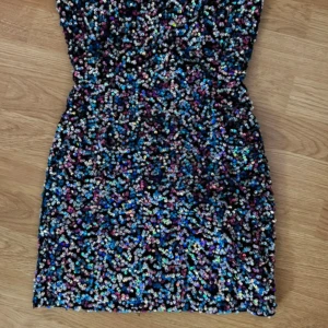 Flerfärgad axelbandslös kortklänning - Säljer en unik axelbandslös kortklänning med ett coolt flerfärgat mönster i blått, lila, rosa och svart. Klänningen har en tight passform och är perfekt för dig som vill sticka ut. Materialet känns mjukt och stretchigt.