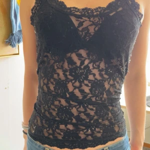 Svart spetslinne - Säljer ett svart, transparent linne i spets med blommigt mönster. Linnet är figurnära på bild men sitter pösigare i verkligheten 