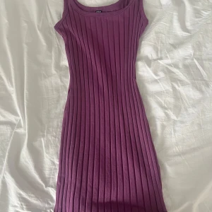 Lila ribbad klänning  - Säljer en kort lila ribbad klänning från SHEIN i storlek S. Klänningen är ärmlös med rund halsringning och har en tight passform. Den är endast använd en gång. 