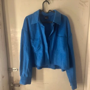 Blå kappa  - Säljer en blå kappa från Gina Tricot med stora bröstfickor och klassisk krage. Jackan har knäppning framtill och långa ärmar. Perfekt för lager-på-lager och en cool vardagslook. Den är i en jätte fin blå färg perfekt nu till sommar/vår