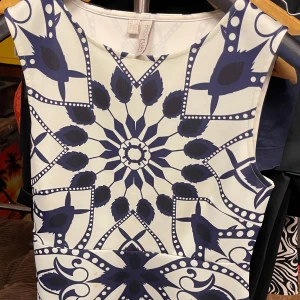 Bodyflirt mönstrad ärmlös klänning stl 42 - Säljer en ärmlös vit klänning med marinblått grafiskt mönster från Bodyflirt. Klänningen har rund halsringning och figurnära passform, perfekt för dig som gillar unika prints och stilren design.
