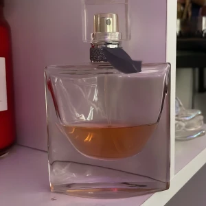 La Vie Est Belle Eau de Parfum - Elegant parfymflaska i genomskinligt glas med en ljusrosa doftvätska. Mindre än halva kvar