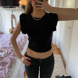 Svart topp med volangärmar från Zara - Svart croppad topp från Zara med korta volangärmar och rund halsringning. Den är ribbad och har en tight passform. Perfekt för sommaren. trendig & slutsåld💞💞