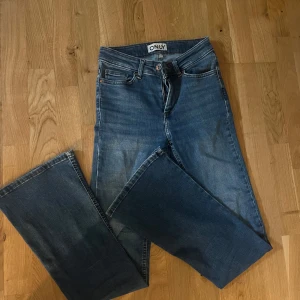Blå bootcut jeans från ONLY - Säljer ett par klassiska blå bootcut jeans från ONLY. Jeansen har normal passform, hög midja och är tillverkade i ett mjukt denimtyg. Perfekta för dig som gillar en tidlös stil med lite utsvängda ben.