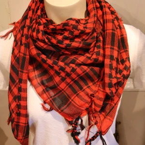Palestina sjal Röd och svart rutig halsduk - Säljer en röd och svart rutig halsduk med klassiskt mönster och fransar i kanterna. Perfekt accessoar för att ge din outfit lite edge och värme. Halsduken är mjuk och lätt att styla på olika sätt.
