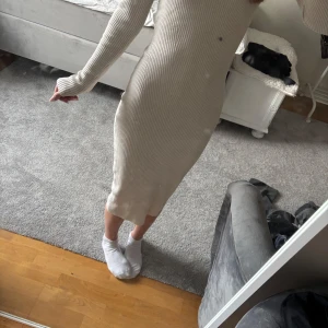 Beige ribbad långklänning - Säljer en beige ribbad långklänning med lång ärm och rund i halsen.  Klänningen har en tight passform och är tillverkad i ett stretchigt material som sitter snyggt på kroppen. Perfekt för dig som gillar en enkel men stilren look.💕