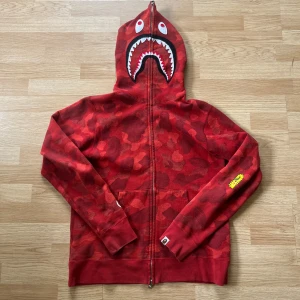 Bape full zip shake hoodie ( AUTHENTIC) - Selling my authentic BAPE Shark hoodie in the iconic red camo colorway. Classic full-zip design that covers the entire hood with the signature shark face. Size: L Condition: Gently used – no major flaws, stains, or tears. 100% authentic Perfect for collectors or anyone who wants a bold streetwear statement piece.
