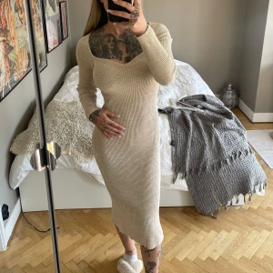 Beige ribbad klänning  - Säljer en beige ribbad klänning med lång ärm och snygg v-ringning. Klänningen har en figurnära passform och en slits baktill för extra rörelsefrihet. Perfekt för dig som gillar stilrena och bekväma plagg. One sixe, väldigt stretchig 