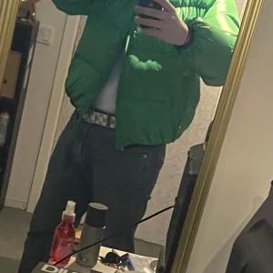Grön pufferjacka från Moncler - Säljer en grön pufferjacka från Moncler med klassisk logotyp på bröstet. Jackan har en glansig finish och är vadderad för extra värme. Perfekt för kyliga dagar och har en modern, oversized passform. Kom med bud eller byten, jackan är äkta, det är en gammal modell därför är det gamla loggan på, den görs inte längre så är väldigt rare