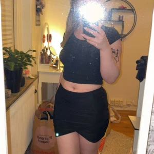 Svart tight kortkjol - Säljer en svart tight kortkjol. Kjolen har en kroppsnära passform. Materialet är polyester. Aldrig använd men säljes då den var för liten för mig. 