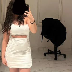 Vit kortklänning med cut-out detaljer - Säljer en vit, tight kortklänning med cut-out detalj under bysten. Knappt använd och i perfekt skick! 