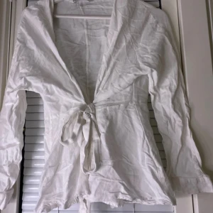 Vit linne blus från Zara - Säljer en vit linne blus från Zara i storlek S. Deb har långa ärmar och knyt i midjan för en snygg passform. Perfekt för vår och sommar, enkel att styla med accessoarer.