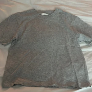 Grå t-shirt från Gina Tricot - En enkel och stilren grå t-shirt från Gina Tricot, basically basics-kollektionen. T-shirten har rund halsringning och korta ärmar, perfekt för en avslappnad look.