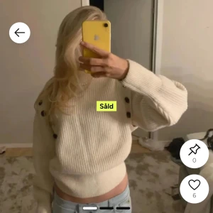 Vit ribbad stickad tröja med knappar - Säljer en vit ribbad stickad tröja med bruna knappar längs axlarna. Tröjan har lång ärm men kan även bäras ärmlös genom att knäppa av ärmarna. Perfekt för dig som vill ha en flexibel och stilren look.