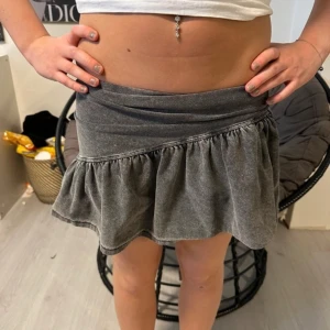 Grå volangkjol - Säljer en grå kortkjol med volanger. Kjolen har en avslappnad passform och är perfekt för en trendig vardagslook. Materialet känns mjukt och bekvämt mot huden.