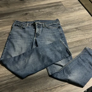 Blå Levis 511 jeans - Klassiska blå Levis 511 jeans med raka ben och femficksmodell. Jeansen har knappgylf och tydliga Levis-detaljer som läderpatch och röd etikett bak. Perfekta för en avslappnad stil.