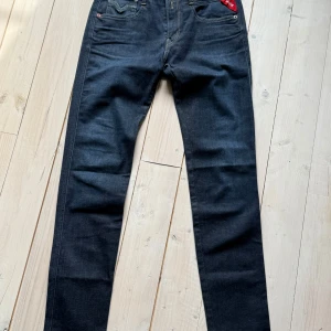 Replay Anbass jeans för Ajax - Mörkblå jeans från Replay i modellen Anbass, specialutgåva för Ajax. Klassisk femficksdesign med rakt snitt och snygga detaljer som röd Ajax-lapp vid fickan. Perfekta för dig som gillar stilrena jeans med sportig touch.