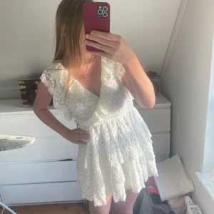 Vit spetsklänning från Nelly - Supersöt vit spetsklänning från Nelly med volangdetaljer och v-ringning. Aldrig använts och är sprillans ny! Storlek S💕