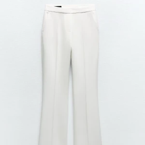 Vita kostymbyxor med bootcut - Snygga vita kostymbyxor med bootcut passform och hög midja. Byxorna har pressveck framtill och diskreta fickor i sidorna. Perfekta för en stilren och trendig look.