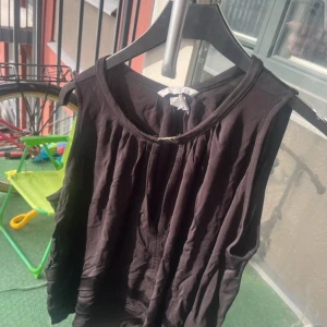 Svart oneshoulder topp - Säljer en svart oneshoulder topp i lätt och luftigt material. Toppen har en asymmetrisk axel och är perfekt för dig som vill ha en stilren och trendig look. Passar till många olika outfits och är enkel att matcha.