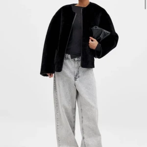 Svart pälsjacka med rund hals - Säljer en stilren svart pälsjacka med rund halsringning och dragkedja framtill. Jackan har en rak passform och är perfekt för dig som gillar en enkel men trendig look. Passar till många olika outfits.