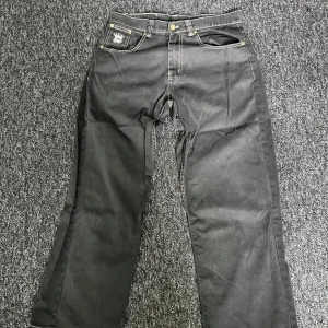 Svarta jeansbyxor med vit text på baksidan - Svarta jeansbyxor från The Urban Chapters med vit dekorativ text 'Only God Can Judge' på baksidan. Klassisk femficksmodell med kontrastsömmar och raka ben. Snygga detaljer