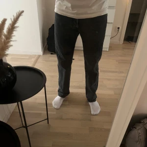 Svarta Levis 501 jeans - Klassiska svarta Levis 501 jeans med rak passform och knappgylf. Jeansen har en tidlös look och är tillverkade i slitstarkt denim. Perfekta för dig som gillar en enkel och stilren stil.