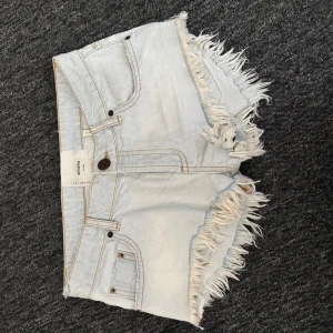 Ljusblå jeansshorts med fransar från One Teaspoon - Säljer ett par ljusblå jeansshorts från One Teaspoon med fransade kanter. Shortsen har låg midja, perfekta för varma dagar. Prislappen är kvar!! Storlek 26!