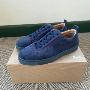 Christian Louboutin Navy Blue  - Säljer ett par mörkblå sneakers i mocka från Christian Louboutin med klassisk röd sula. Dock så har sulan på båda skorna minimala skador. Kvitto kan visas vid behov. Pris kan självklart diskuteras.