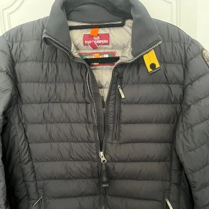 Svart pufferjacka från Parajumpers - Säljer en svart pufferjacka från Parajumpers med gul detalj vid kragen och patch på ärmen. Jackan har dragkedja framtill och quiltad design. Pris diskuteras vid snabb affär, vid frågor är det bara och höra av sig 👍 