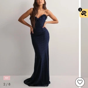 Marinblå långklänning med öppen rygg från Nelly  - Säljer en slutsåld marinblå långklänning med tunna axelband och v-ringning. Klänningen har en elegant öppen rygg och figurnära passform, perfekt för bal eller fest. Materialet har en lätt struktur och ger en lyxig känsla. Aldrig använd bara provad. Prislapp kvar