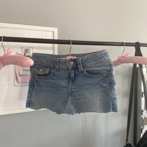 Blå jeanskjol från Gina Tricot - Snygg ljusblå jeanskjol från Gina Tricot med rå kant nertill och klassiska fickor både fram och bak. Kjolen har bälteshällor och knappstängning. Jag har gjort kjolen själv men den är jätte fin ändå.