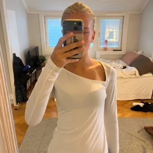 Vit oneshoulder topp från H&M - Säljer en vit långärmad topp från H&M i storlek XS. Modellen har en snygg oneshoulder-skärning som ger en cool asymmetrisk look. Tunn och mjuk, perfekt att styla med jeans eller kjol. Materialet är stretchigt och känns skönt mot huden.