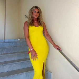 Gul långklänning med slits - Säljer en snygg gul långklänning med v-ringad hals och smala axelband. Klänningen har en figurnära passform och en slits framtill som ger en cool touch. Perfekt för sommarens alla tillfällen och riktigt skön att bära. Fråga gärna om fler bilder eller mått!