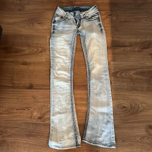 Bootcut jeans - Så snygga lågmidjade bootcut jeans i ljusblå färg. Har två knappar på framsidan och flap pockets där bak. Står ingen storlek men skulle säga xs, midjemåttet är 33 cm tvärsöver 💕