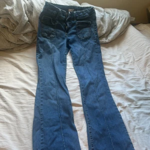 Blå bootcut jeans från Nelly storlek 40 men passar även 38 eftersom den är små i storlek - Pris kan diskuteras!Snygga blå bootcut jeans från Nelly med coola fickdetaljer framtill och klassiska bakfickor. Jeansen har glittriga knappar i midjan och markerade sömmar längs benen. Perfekt för dig som gillar en retro vibe och vill sticka ut lite extra.