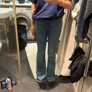 Blå bootcut jeans - Snygga blå jeans med bootcut passform. Jeansen har klassisk femficksdesign och är tillverkade i ett mjukt denimtyg som sitter bekvämt. Perfekta för dig som gillar en retro vibe och vill ha ett par jeans som framhäver benen.