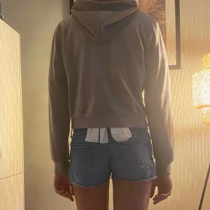 Beige zip jacka  - Jättefin jacka i ett lent material, jackan har en silvrig dragkedja, huva och och ett paljettryck på framsidan.