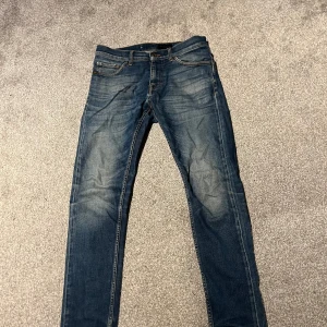 Tiger of Sweden blå jeans slim fit - Snygga blå jeans från Tiger of Sweden med klassisk femficksdesign och brunt läderpatch bak. Jeansen har slim fit och raka ben med lätt slitning framtill för en cool look. Perfekt för dig som gillar stilrena och moderna jeans.