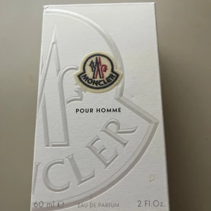 Moncler Pour Homme Eau de Parfum 60ml - Exklusiv herrparfym från Moncler, Pour Homme, 60 ml. Flaskan är i metalliskt silver med räfflad design och Monclers ikoniska logotyp framtill. Kommer i en stilren vit kartong med broderad logga. Perfekt för dig som gillar lyxiga och moderna dofter. (Sprayat ca 3 gånger)