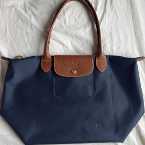 Longchamp Väska  - Säljer nu min fina väska från longchamp då jag vill köpa ny skolväska. Den är i väldigt fint skick för att ha varit använd i nästan ett helt skolår, det lortiga inuti tvättas bort så bra som möjligt innan de postas! Köpt på NK’s hemsida!🥰