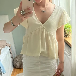 Ljusbeige blus med v-ringning - Supersöt ljusbeige blus med v-ringad hals och volang nedtill från GinaTricot!🫶🏻