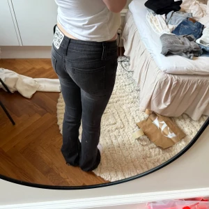 Svarta bootcut jeans  - Säljer ett par svarta bootcut jeans med klassisk femficksdesign och låg midja. Jeansen har en snygg passform som sitter tight upptill och släpper ut vid bensluten. Perfekta till vardags med en enkel t-shirt. 